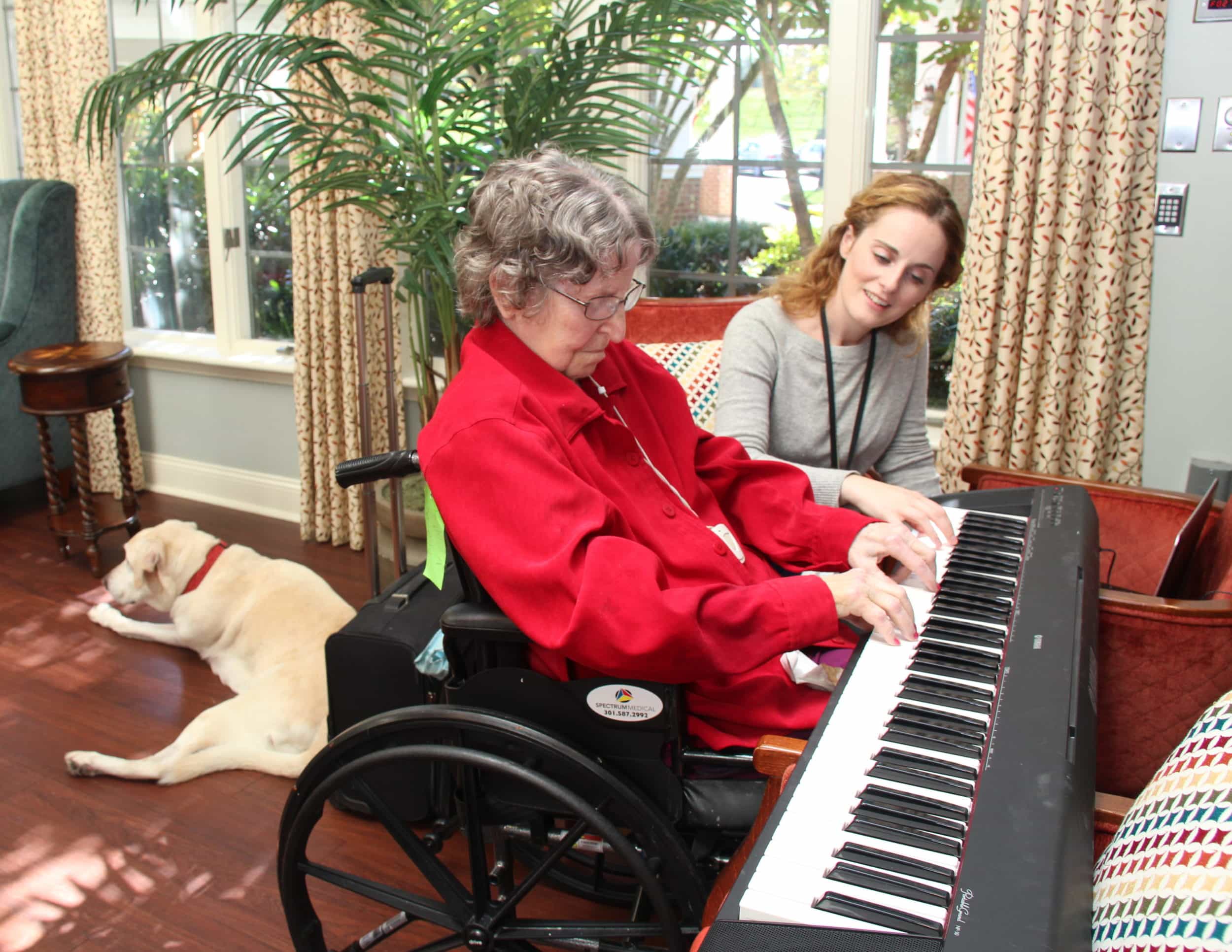 Kensington Park assisted living resident plays piano with full time music therapist, Jessica