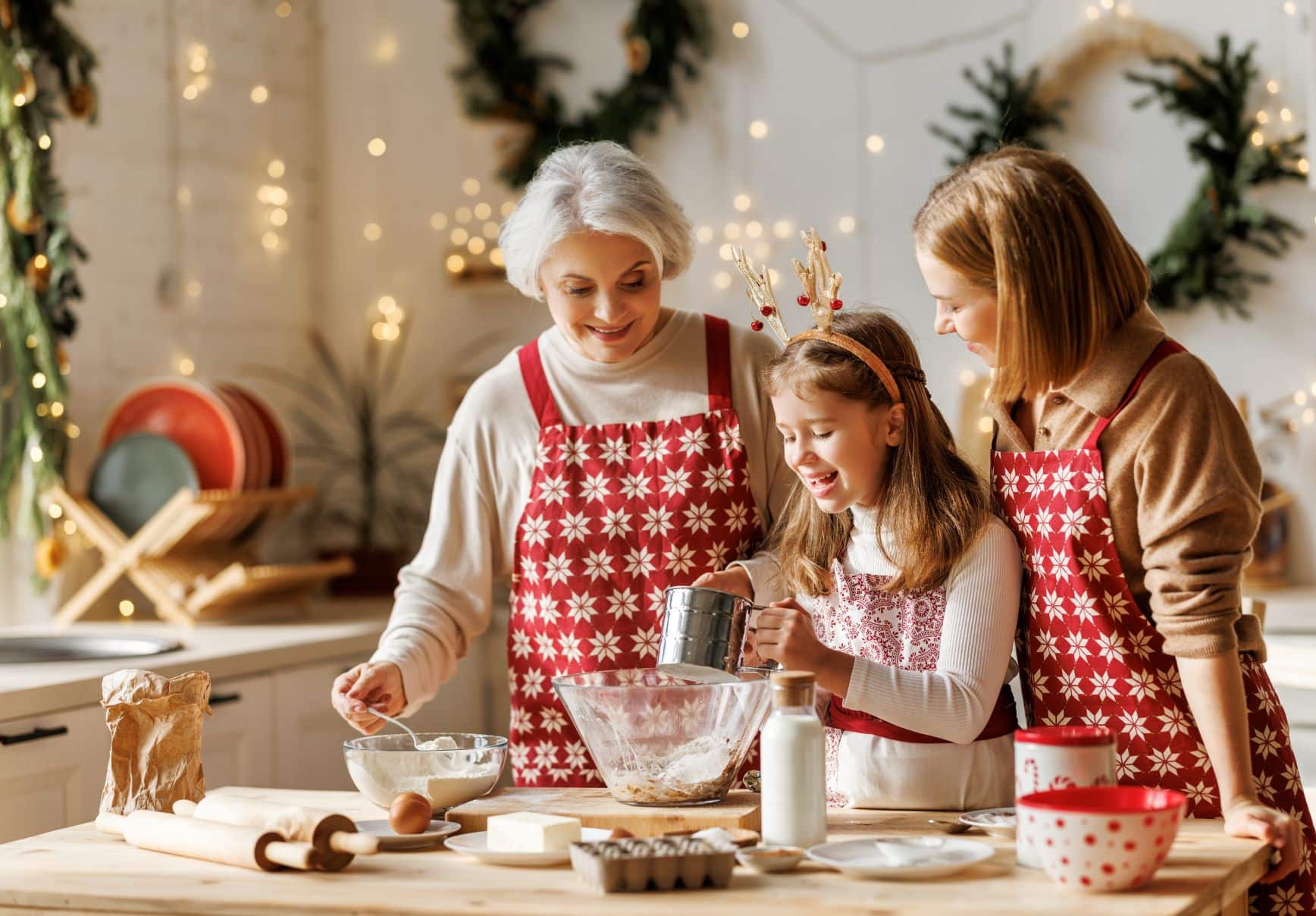 elderly woman, adult woman, and young girl baking together