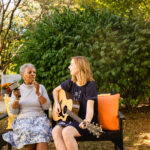 Women playing guitar next to senior lady