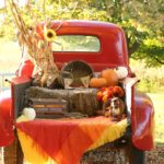 red truck with hay bales, pumpkins, and flowers in bed