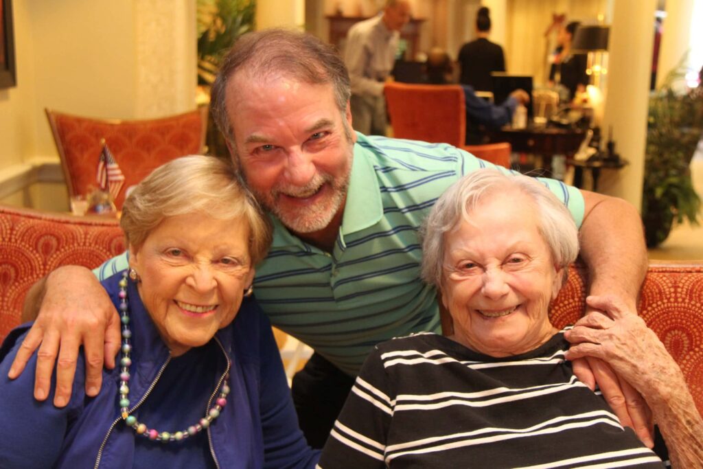 Three smiling friends and family at Kensington Park event.