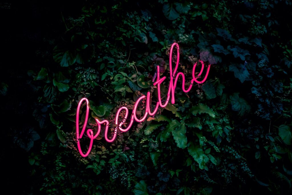 neon breathe sign against green wall background