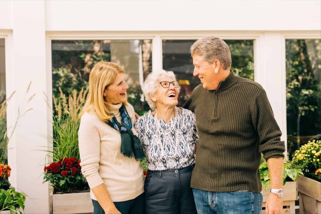 man and woman standing with older woman smiling together