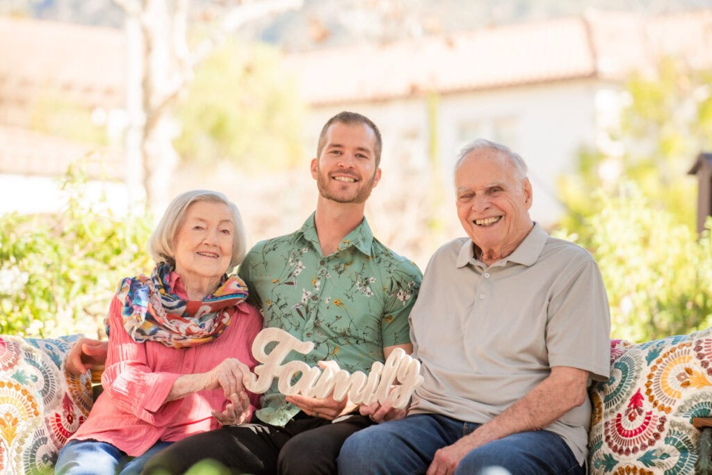 old couple with man holding sign that says family
