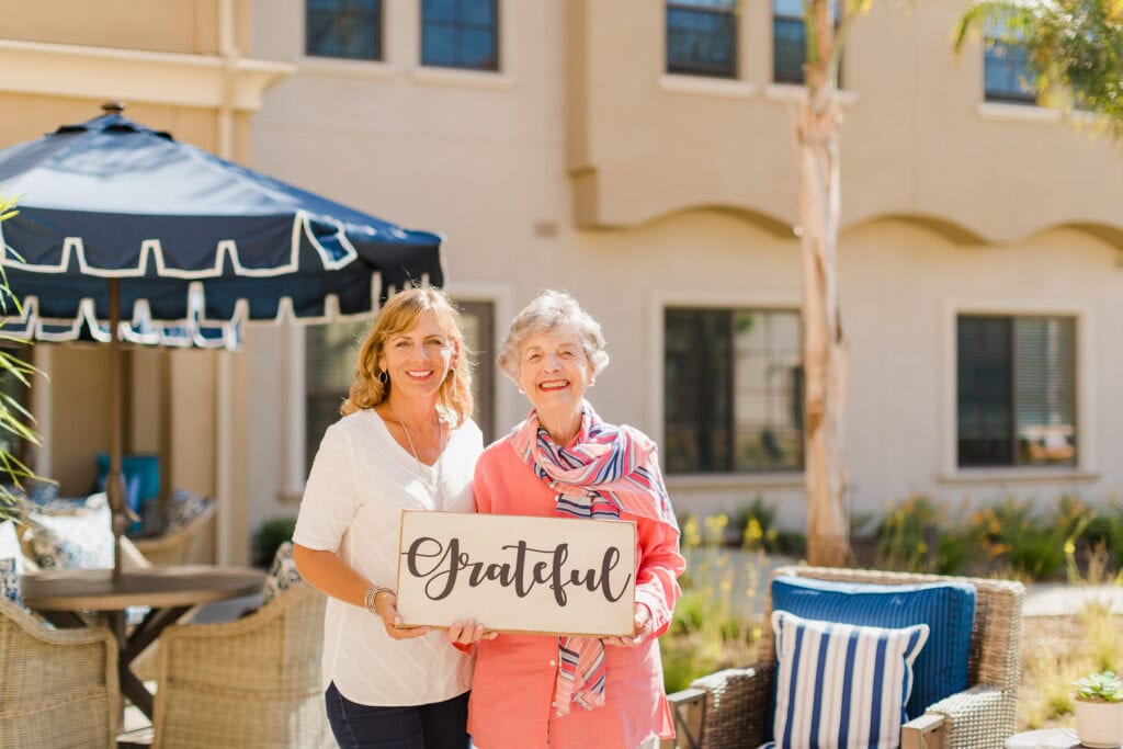 two women holding a sign that says grateful