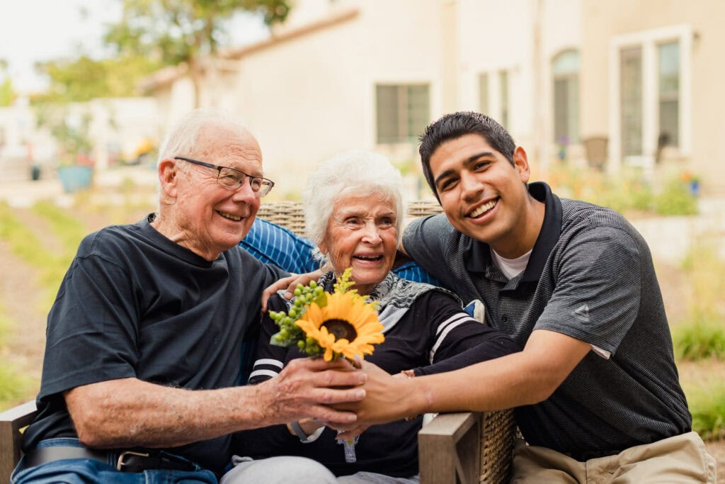 older couple with young man holding a sunflower